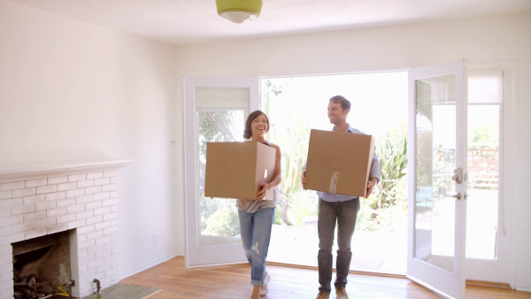 a young couple carrying boxes while moving into their new house