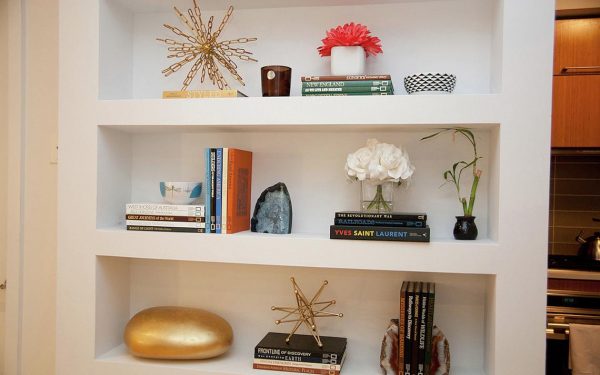 a simple white book shelf with books and decorative items on it