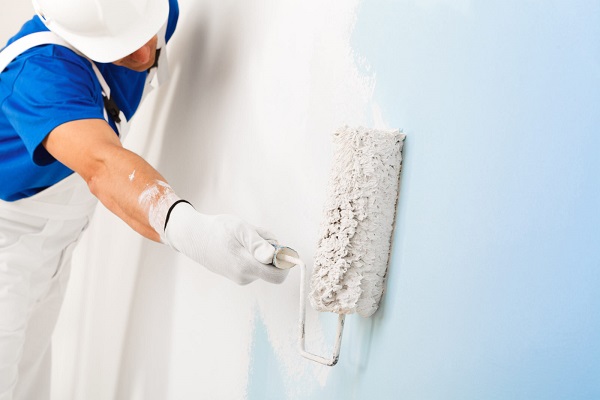 A handyman painting a wall with a paint roller